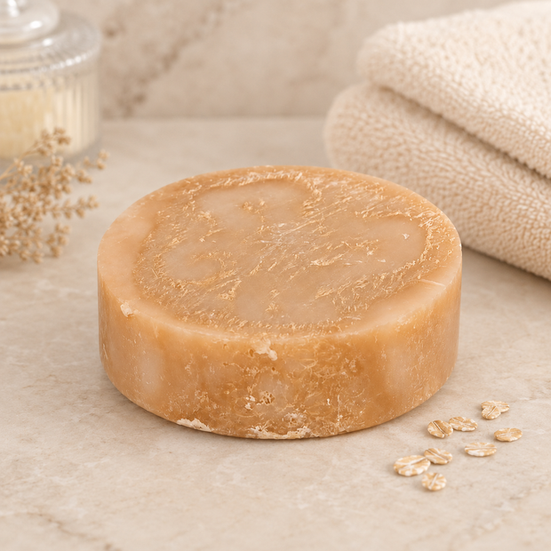 Bar of soap on a marble surface with oats and a towel in the background