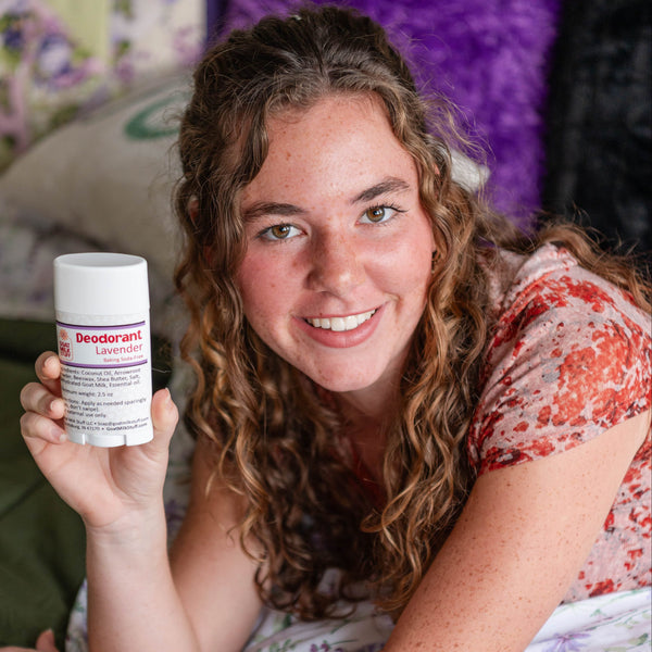 Woman lying on a bed holding a container of deodorant