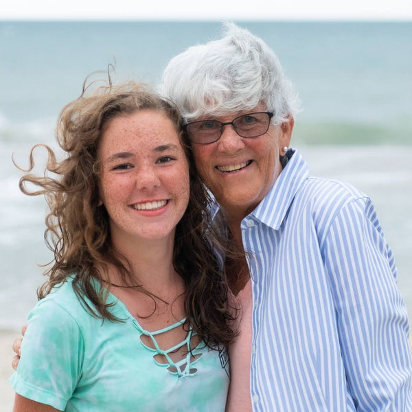 Two people standing on a beach with ocean waves in the background