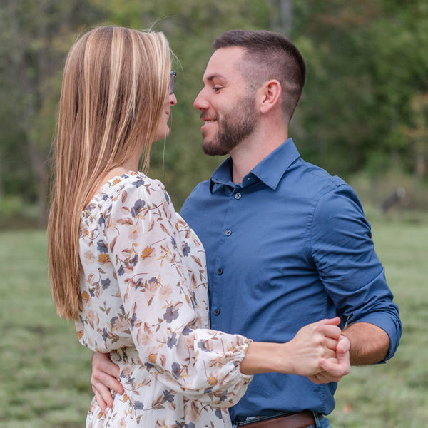Couple standing in a field with trees in the background