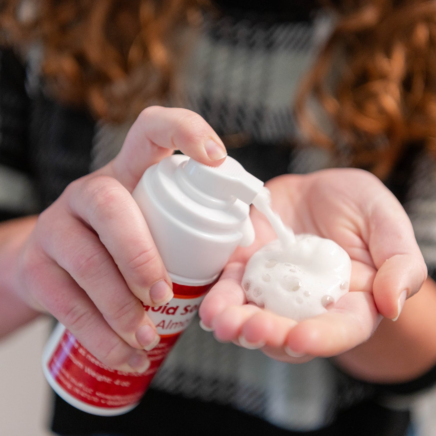 Person applying a white foam from a foamer into their hand
