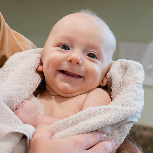 Man holding a baby wrapped in a towel in a kitchen