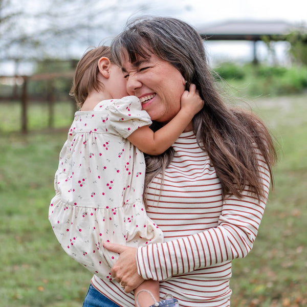 Grandma holding a child in an outdoor setting with trees and grass.