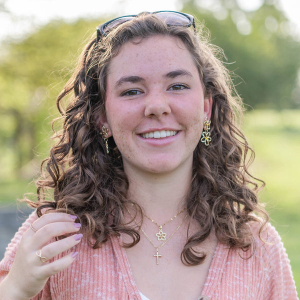 Woman with curly hair standing outdoors in a park-like setting
