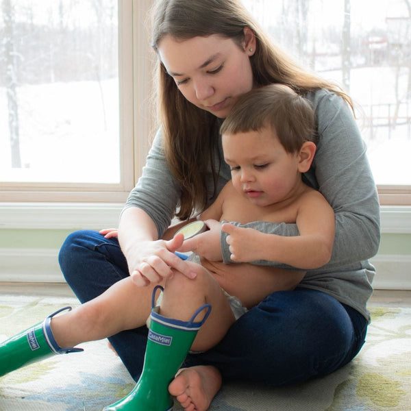 Mother applying balm to childs knee