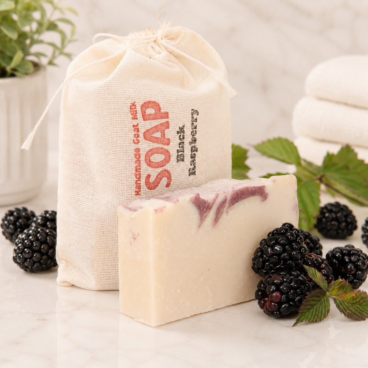 Bar of goat milk soap with black raspberries and a drawstring bag labeled 'Handmade Goat Milk Soap' on a light background.