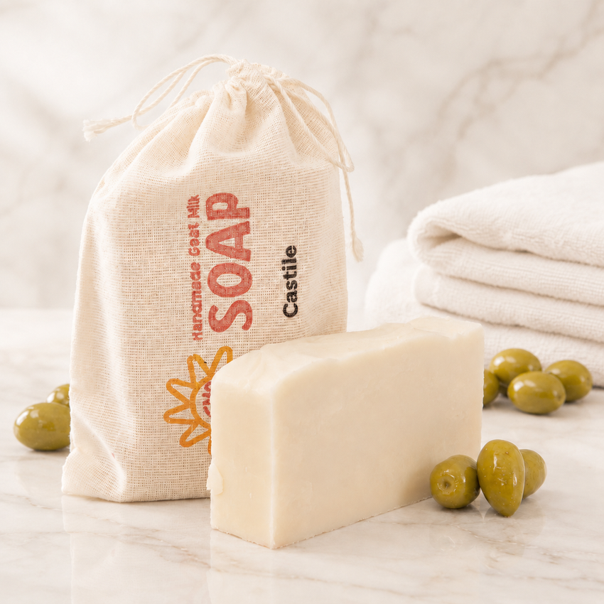 Bar of goat milk soap with a drawstring bag labeled 'Castle Soap' and olives on a light background