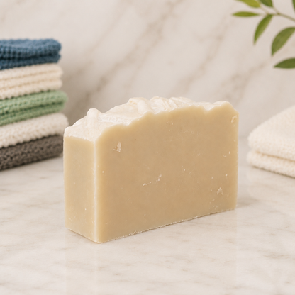 Bar of goat milk soap with towels in the background on a neutral surface