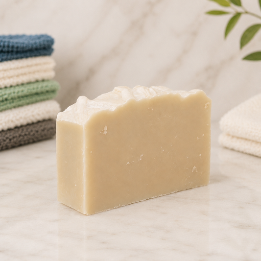 Bar of goat milk soap with towels in the background on a neutral surface