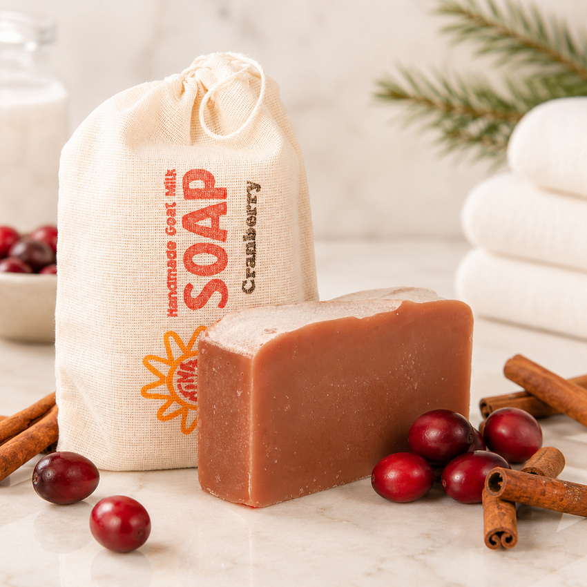 Bar of goat milk soap with a drawstring bag labeled 'Soap' and cranberries on a marble surface.
