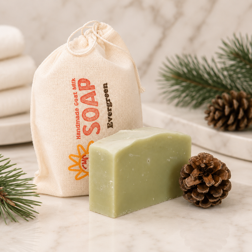 Green bar of goat milk soap with a drawstring bag labeled 'Evergreen Soap' and a pine cone on a light background.