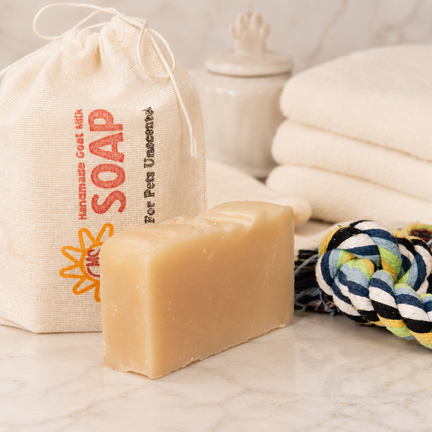 Bar of goat milk soap with a drawstring bag labeled 'Handmade Goat Milk Soap' and a rope toy in the background.