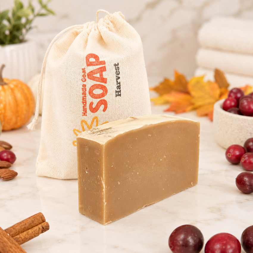 Bar of goat milk soap with a 'Handmade Soap Harvest' drawstring bag on a surface with autumn-themed items.