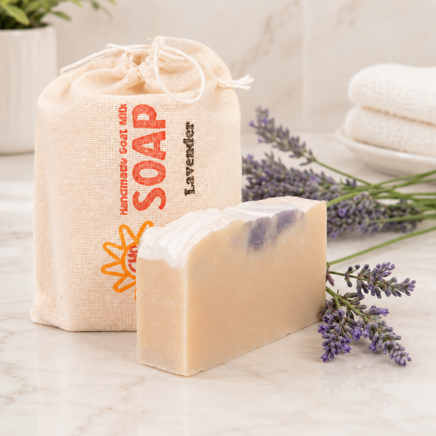 Bar of goat milk soap with lavender fragrance next to a drawstring bag labeled 'Soap' on a marble surface.