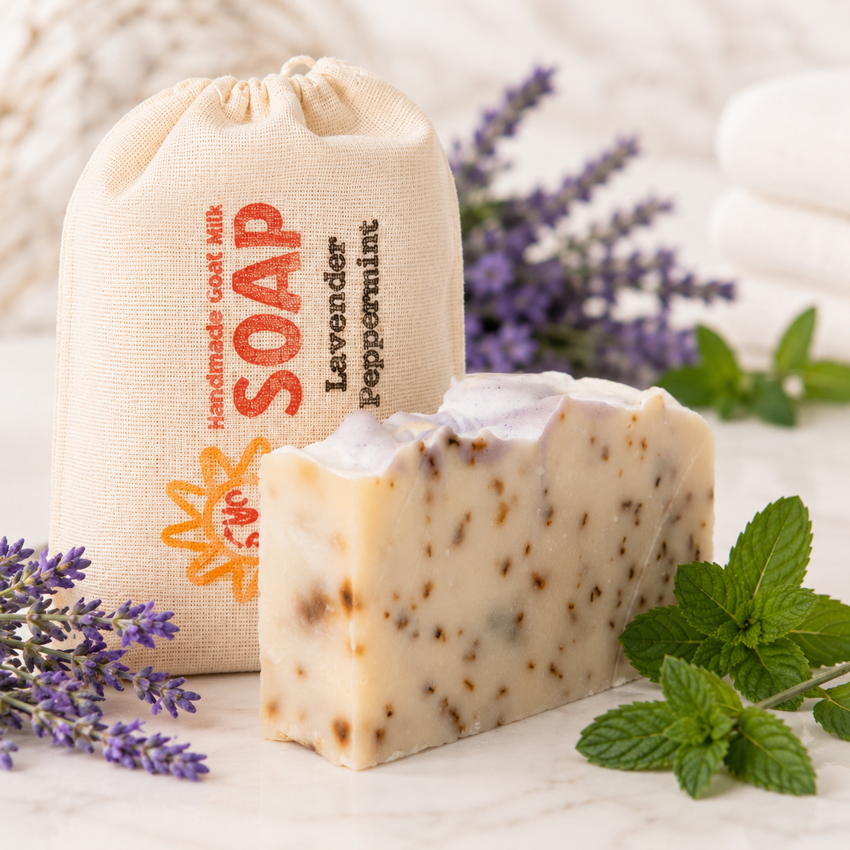 Bar of goat milk soap with a drawstring bag labeled 'Handmade Soap' and lavender flowers on a light background.