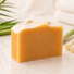 Bar of goat milk soap on a light surface with greenery in the background