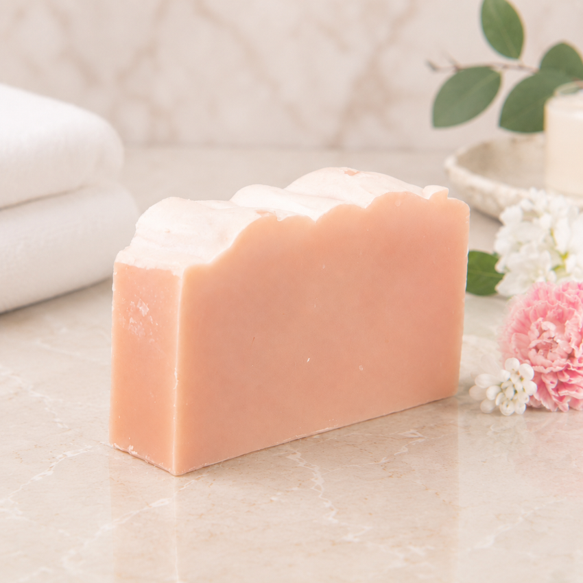 Bar of goat milk soap with a decorative border of flowers and leaves on a light surface.