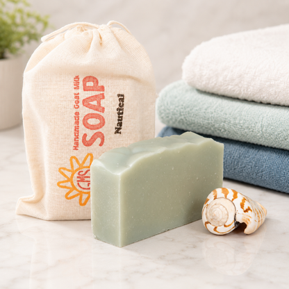 Bar of goat milk soap with a drawstring bag labeled 'Soap' and folded towels on a light surface.
