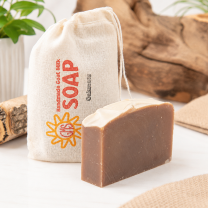 Bar of goat milk soap with a cloth bag labeled 'SOAP' on a light background