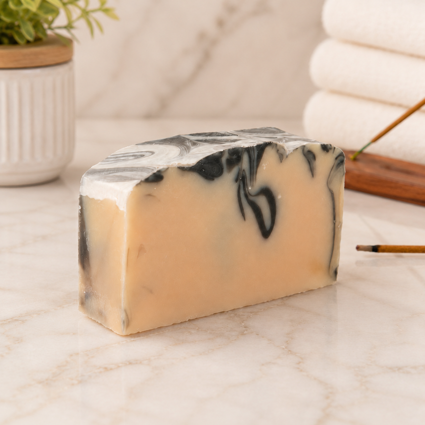 Marble-patterned goat milk soap bar on a marble surface with a blurred background