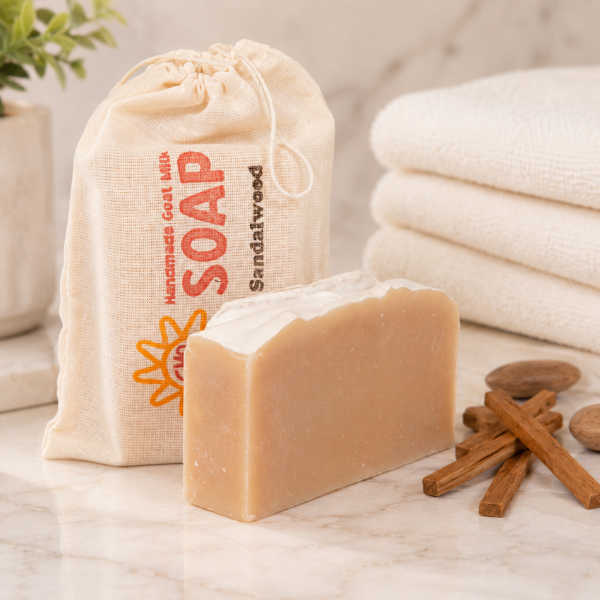 Bar of goat milk soap with a drawstring bag labeled 'Soap' and cinnamon sticks on a marble surface.