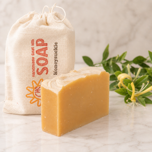 Bar of goat milk soap with a drawstring bag labeled 'Soap' on a marble surface.