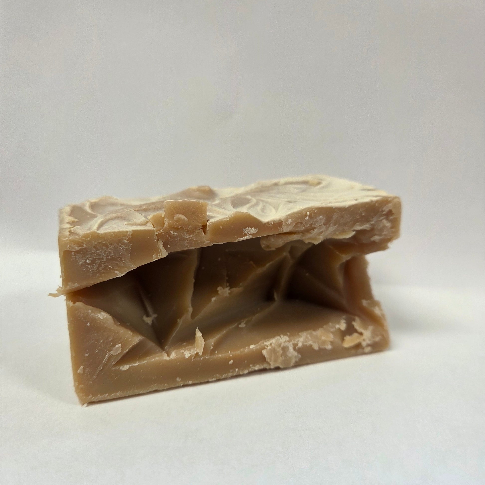 Bar of irregular shaped goat milk soap with a textured surface on a white background