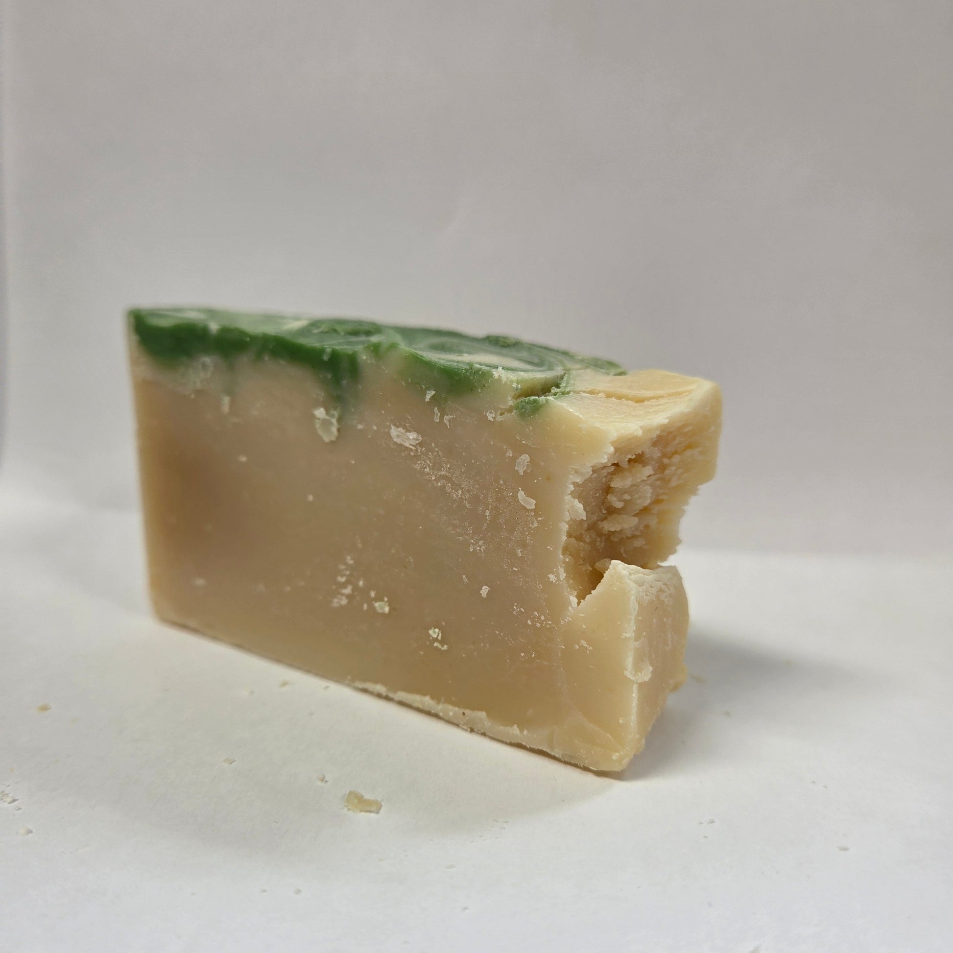 Bar of goat milk soap with green specks on a white background