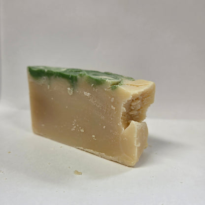 Bar of goat milk soap with green specks on a white background