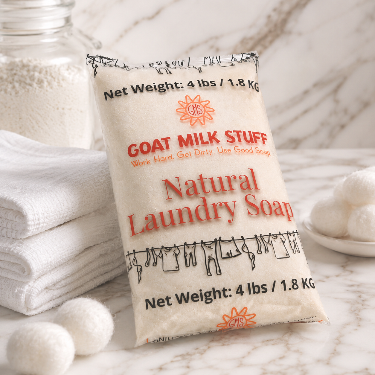 Bag of goat milk natural laundry soap with text on a marble surface with towels and soap bars.