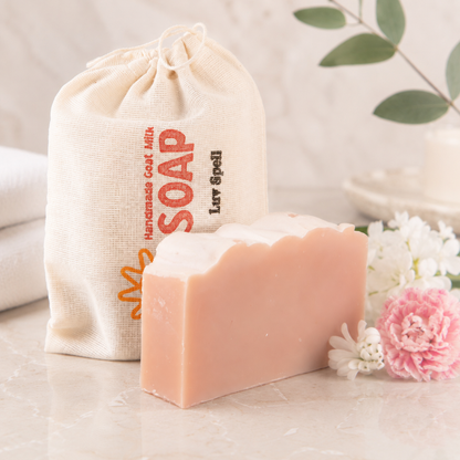 Bar of soap with a drawstring bag labeled 'SOAP' on a light surface with flowers.
