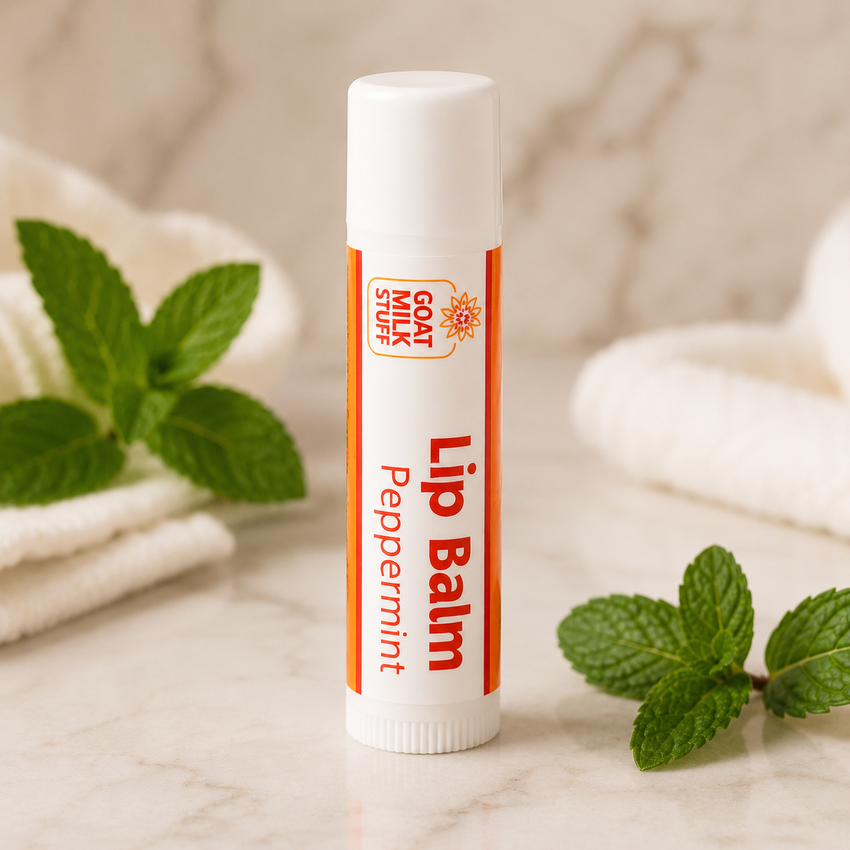 Lip balm stick with peppermint flavor on a marble surface with mint leaves.