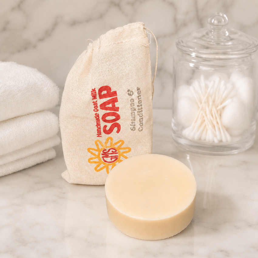 Bar of soap with a cloth bag labeled 'Handmade Goat Milk Soap' on a marble surface.