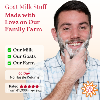 Man with a beard and mustache with shaving cream, smiling, with text about goat milk product on a beige background.