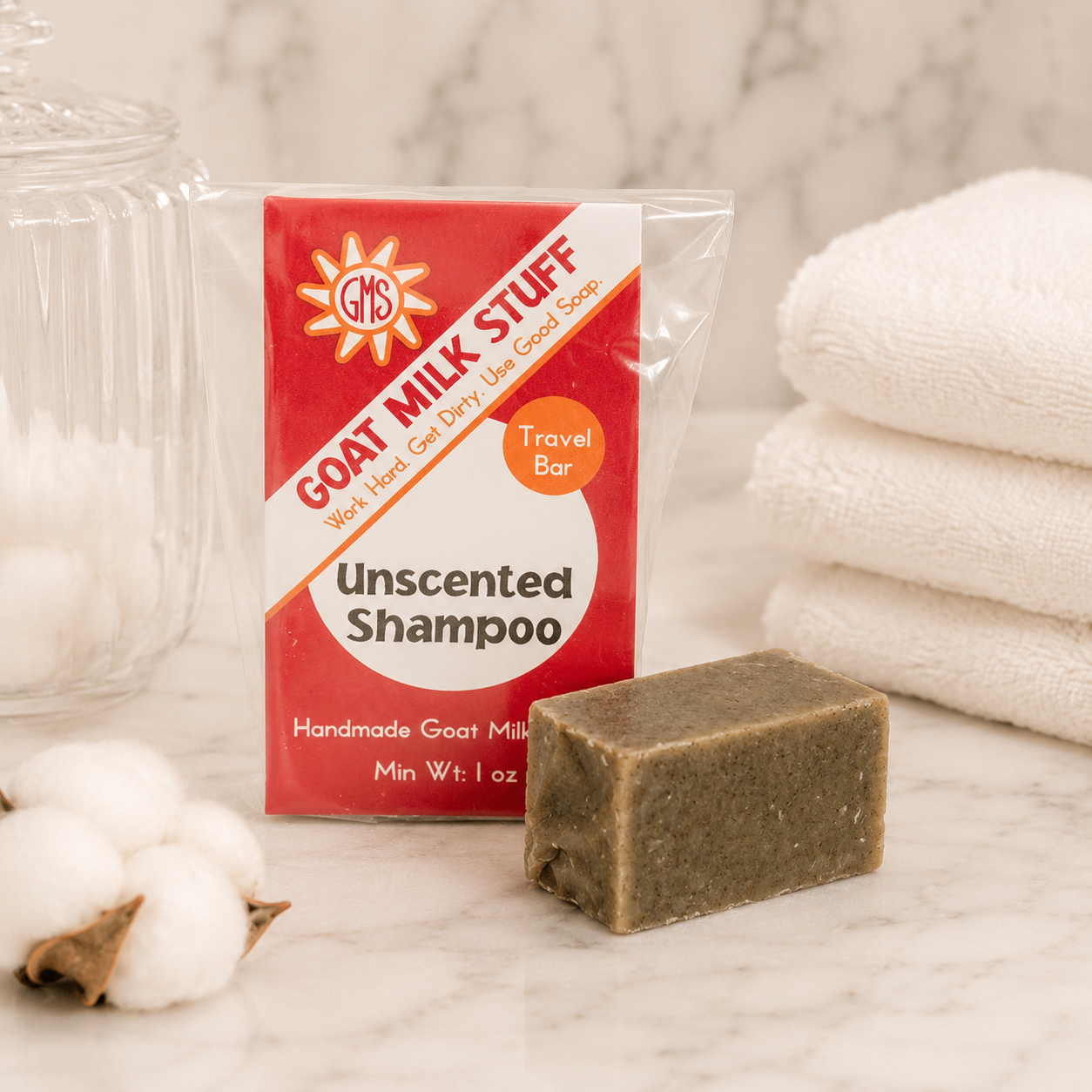 Goat Milk Stuff shampoo bar with packaging on a marble surface with cotton and towels.