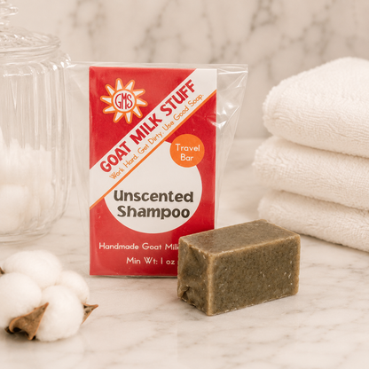 Goat Milk Stuff shampoo bar with packaging on a marble surface with cotton and towels.