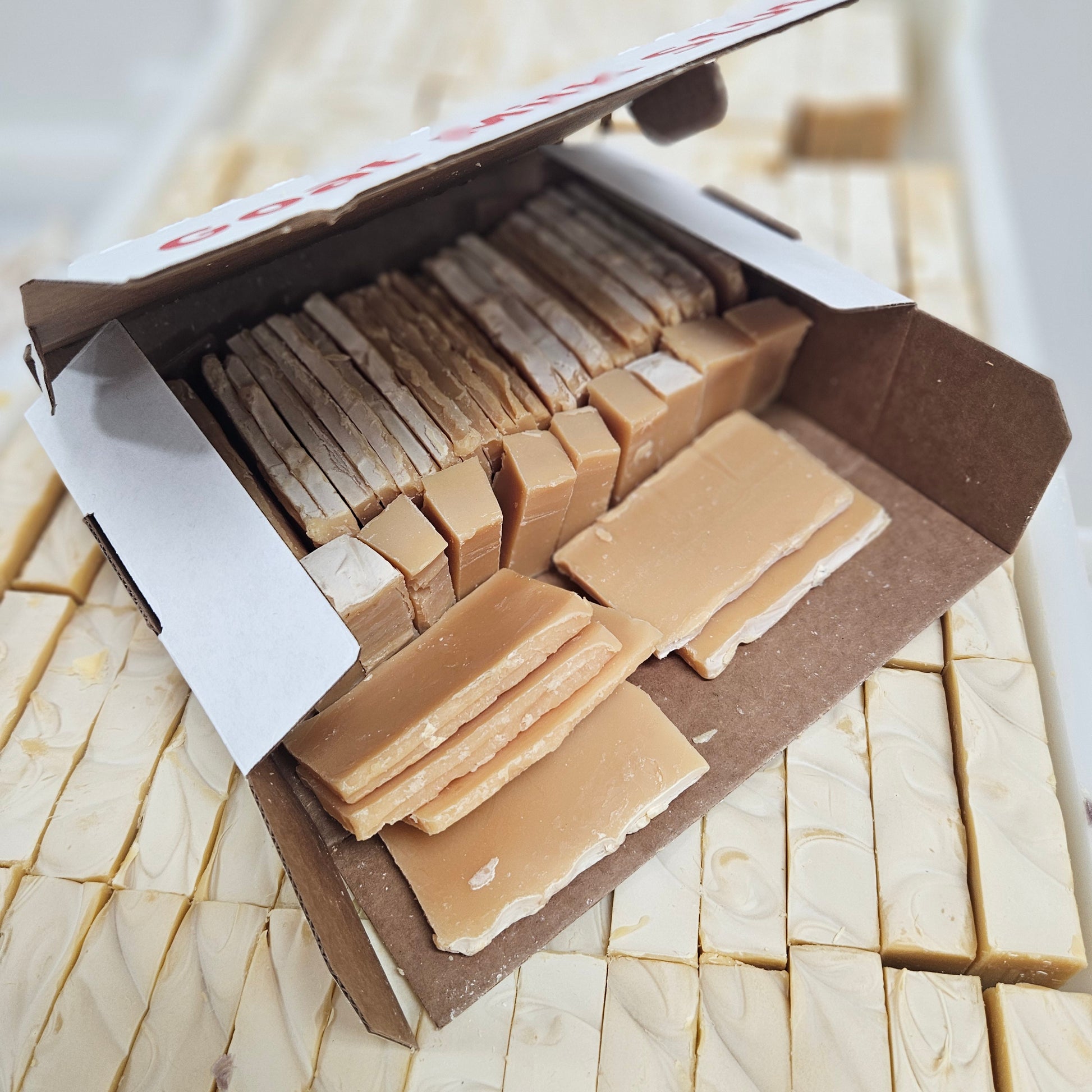 Goat milk soap end pieces in a box on a tray of soap bars