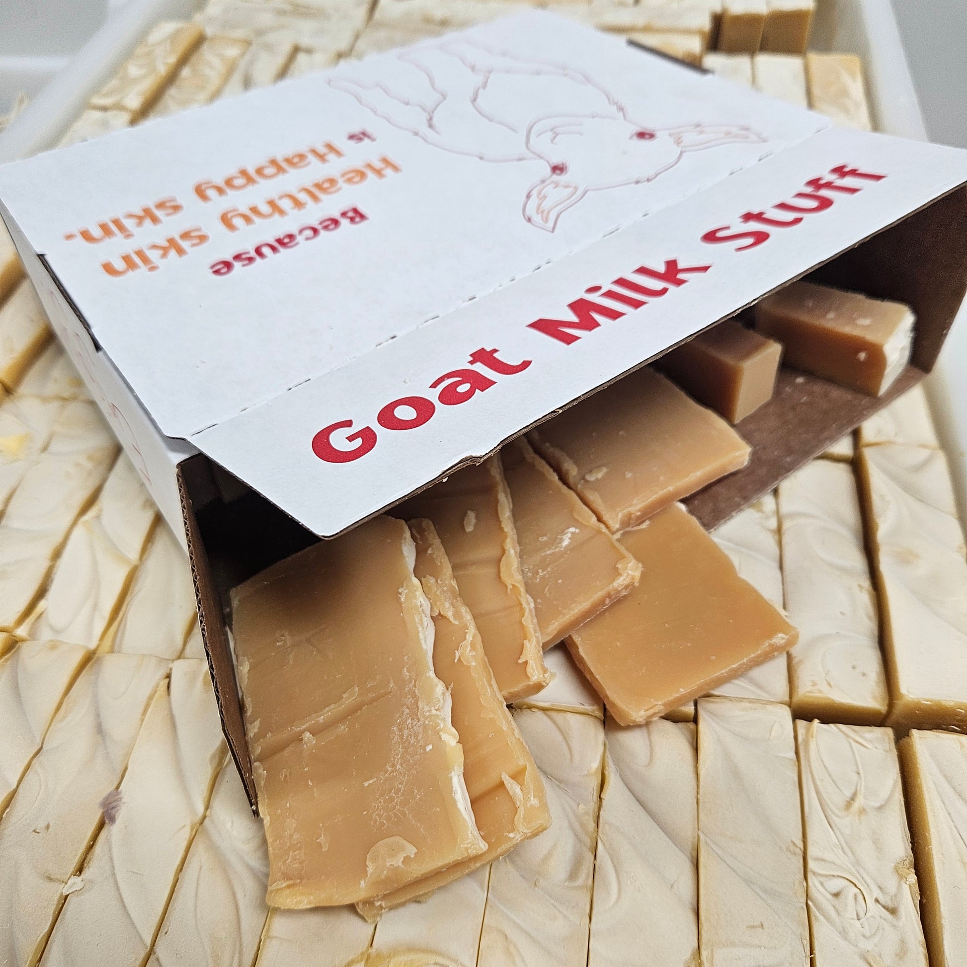 Goat milk soap end pieces in a box on a tray of soap bars