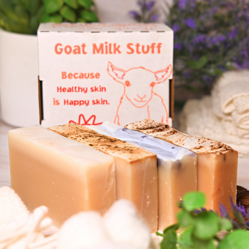 Goat milk soap bars with a box labeled 'Goat Milk Stuff' on a soft, blurred background.