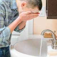 washing face at sink with goat milk soap for soft skin