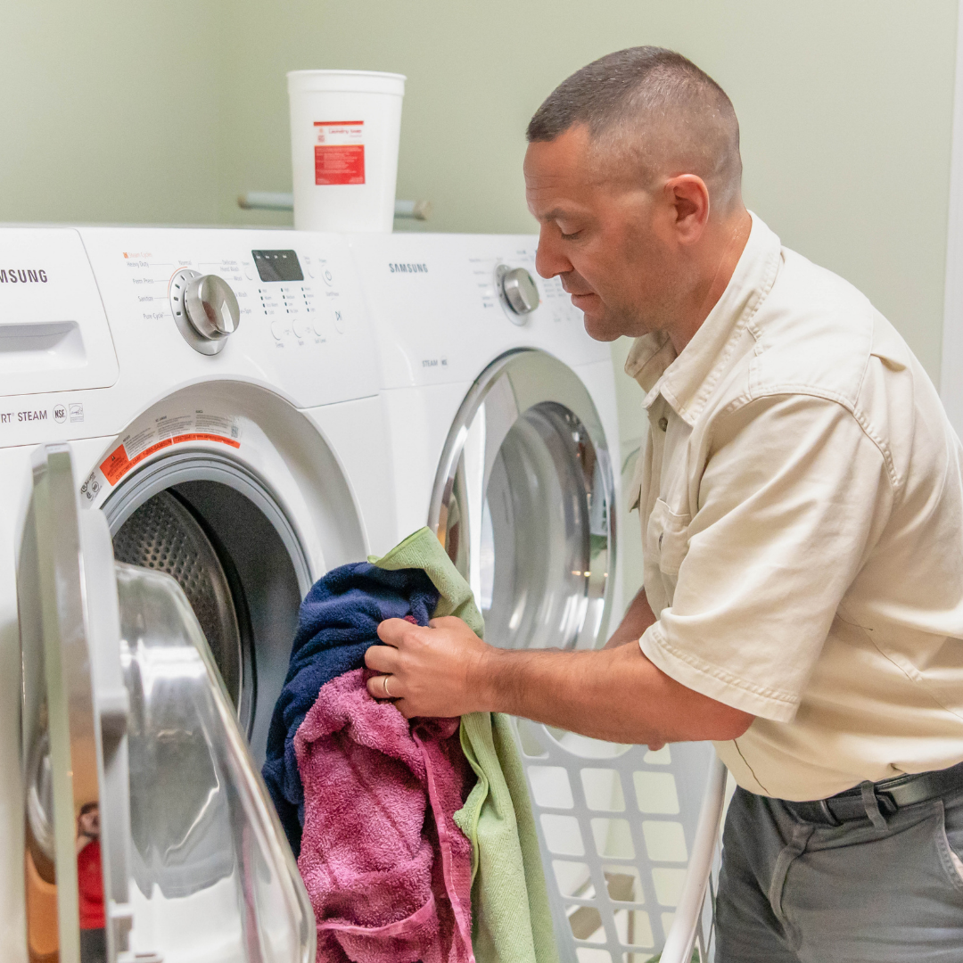 man putting laundry in washing machine