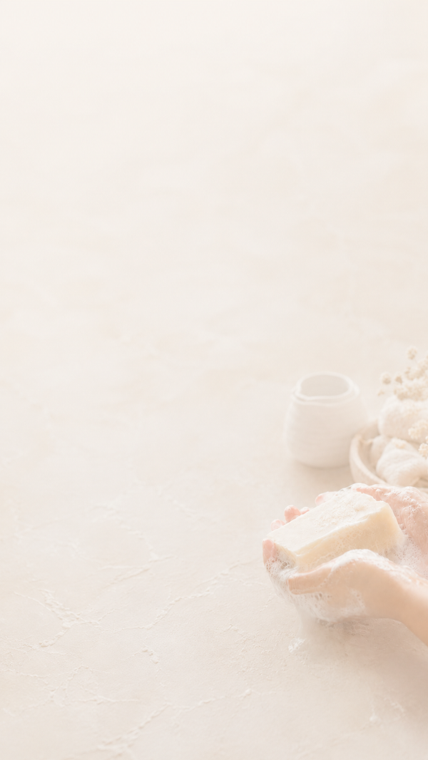 Lathered hand holding a Goat Milk Soap bar against a white background